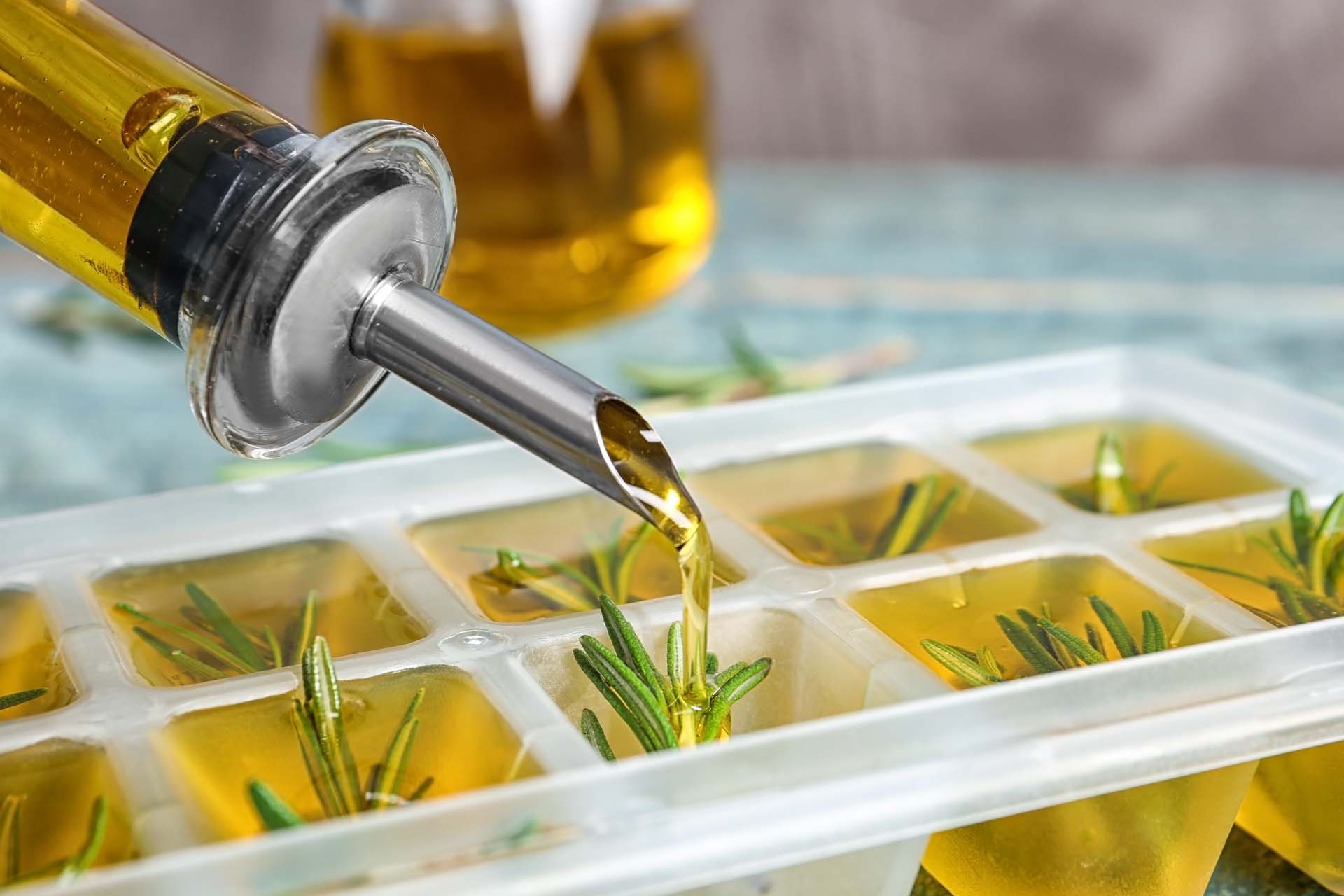Pouring olive oil into an ice tray with herbs to freeze.