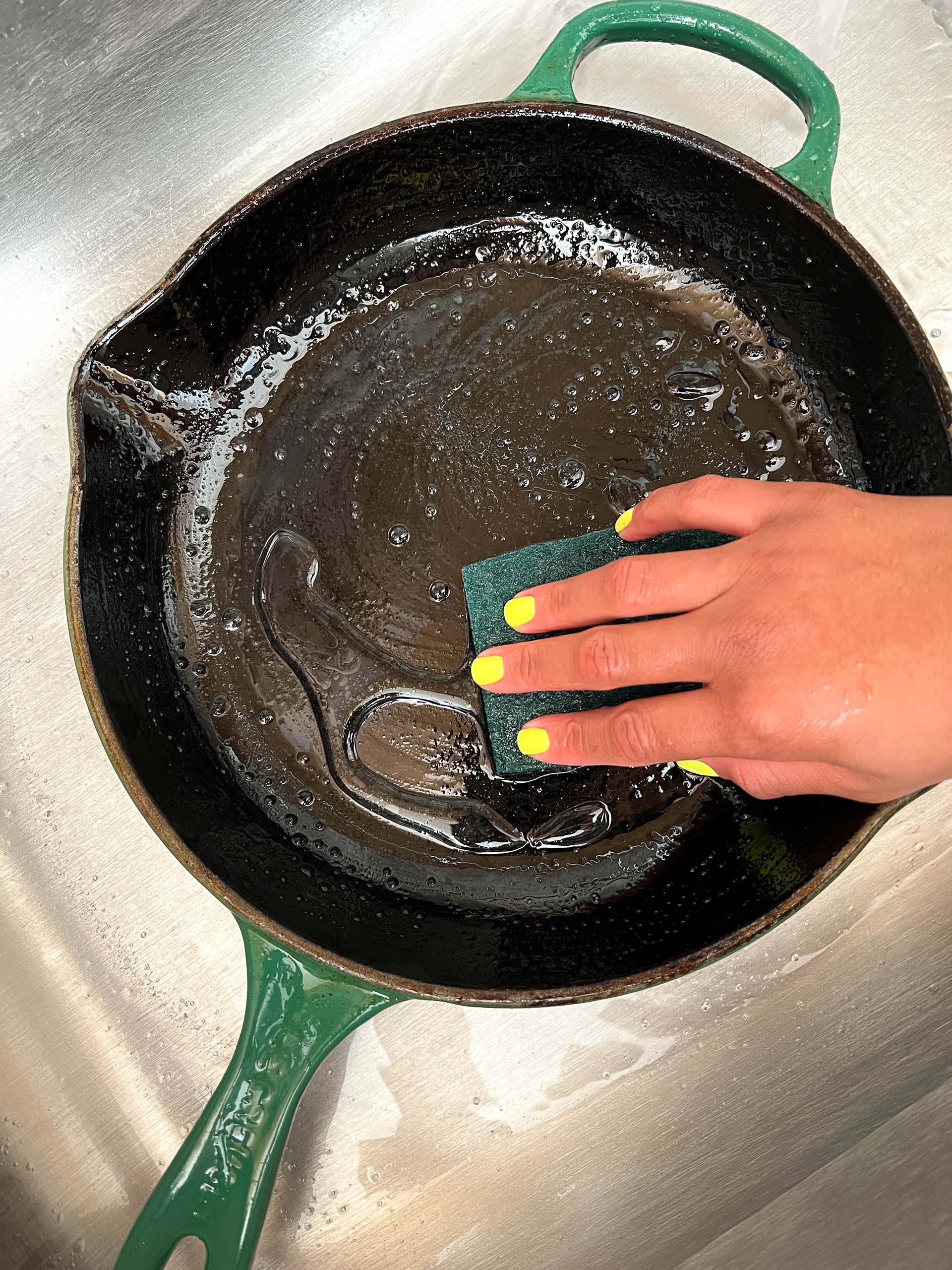 Cast iron skillet in the sink being washed.